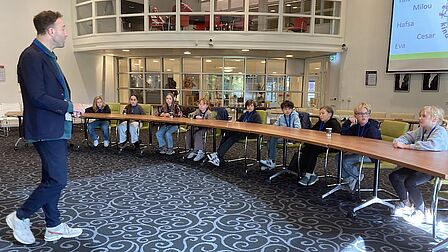 De kindergemeenteraad krijgt uitleg van een ambtenaar over de inrichting van een speelveld.