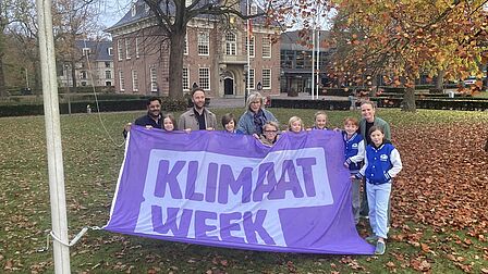 Eva, Pieter, Milou, Dana, César, Elisa en Mia hezen de vlag voor de Klimaatweek met Falgun Binnendijk, Sam Meerhoff en Eveline Stam