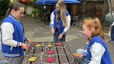 Kinderen van de kindergemeenteraad spelen boter kaas en eieren op het terrein van de kinderboerderij.