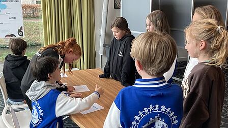 Kinderen uit de gemeenteraad bekijken de stempassen tijdens het oefenen met stemmen in het gemeentehuis