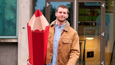 Jonge man met groot rood potlood gemeenteraadsverkiezingen 2026